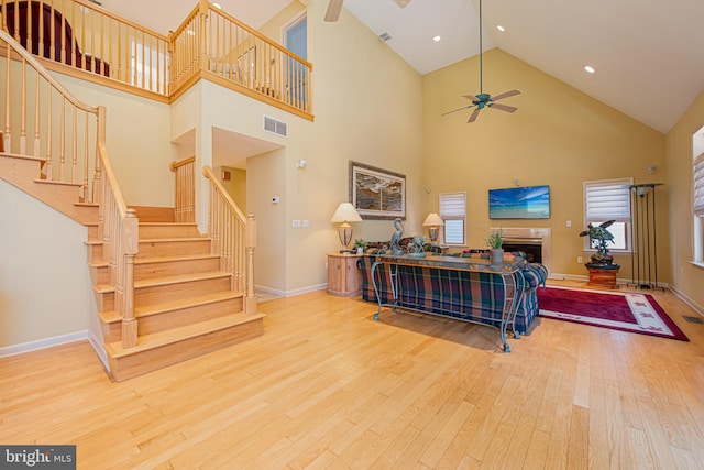 living room featuring hardwood / wood-style floors, a towering ceiling, and ceiling fan