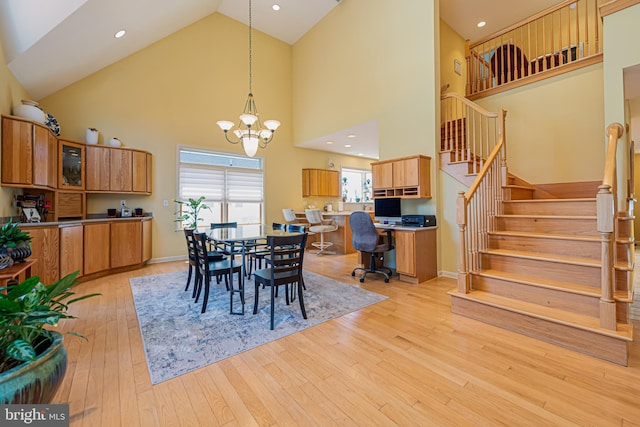 dining room featuring an inviting chandelier, light hardwood / wood-style flooring, and high vaulted ceiling