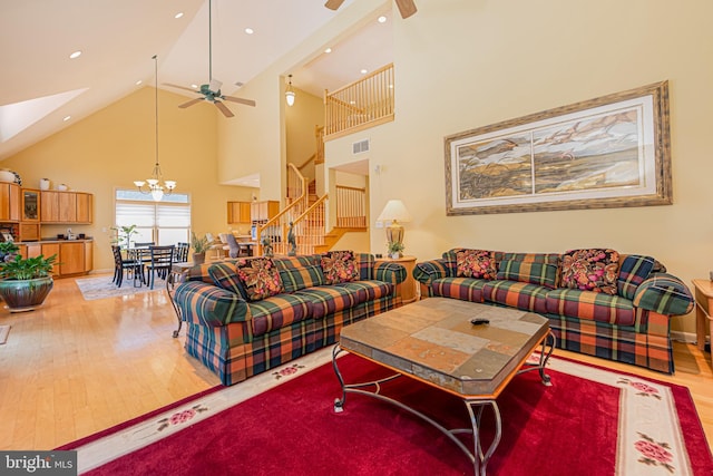 living room featuring hardwood / wood-style flooring, ceiling fan with notable chandelier, and high vaulted ceiling