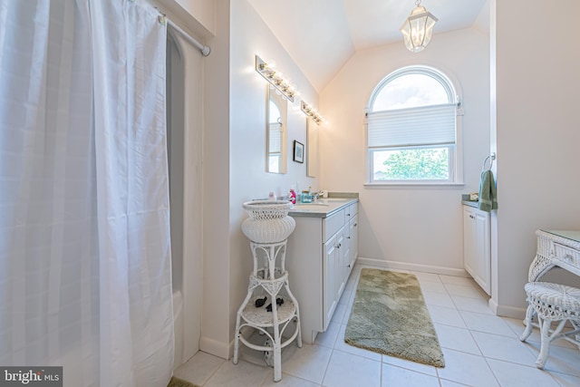 bathroom with vaulted ceiling, vanity, and tile patterned floors