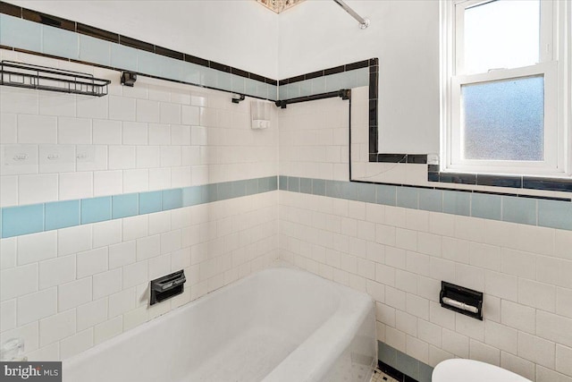 bathroom featuring toilet, a bathing tub, and tile walls