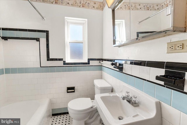 bathroom with toilet, sink, and tile walls