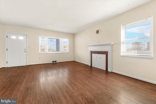 unfurnished living room featuring a healthy amount of sunlight, hardwood / wood-style floors, and a fireplace