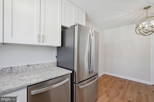 kitchen featuring pendant lighting, light hardwood / wood-style flooring, white cabinetry, stainless steel appliances, and light stone countertops