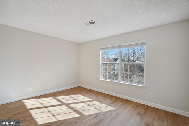 spare room featuring light hardwood / wood-style flooring and a textured ceiling