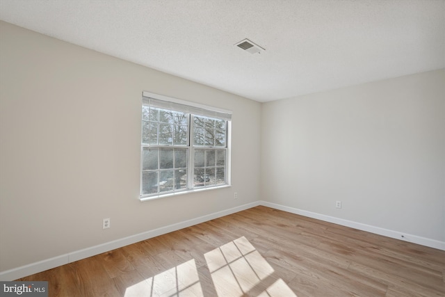 unfurnished room featuring light hardwood / wood-style floors and a textured ceiling