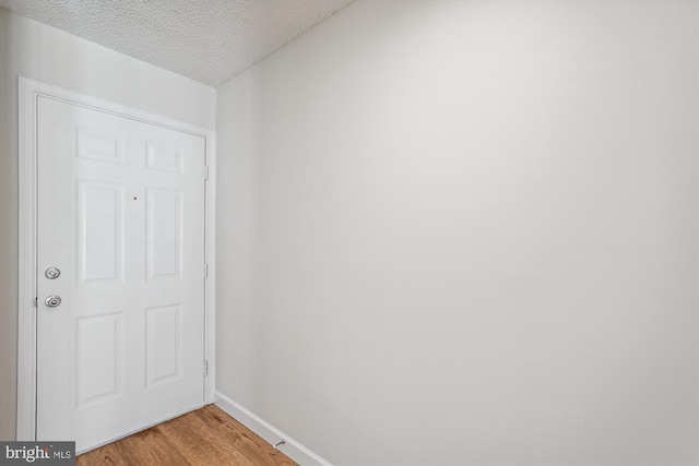 doorway with light hardwood / wood-style flooring and a textured ceiling