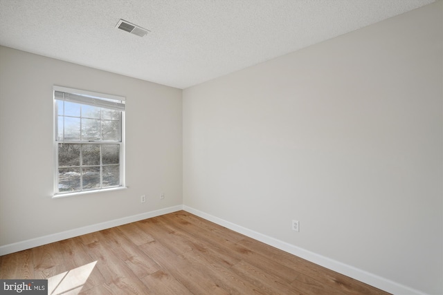 unfurnished room with light hardwood / wood-style floors and a textured ceiling