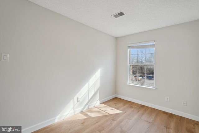 empty room with light hardwood / wood-style floors and a textured ceiling