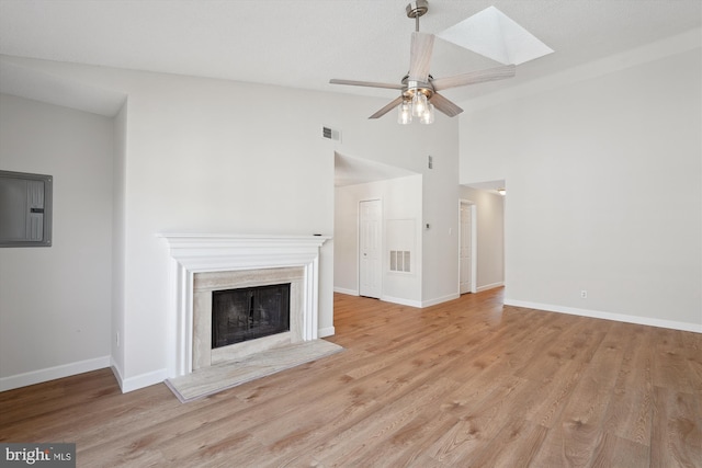 unfurnished living room featuring light hardwood / wood-style flooring, a premium fireplace, ceiling fan, electric panel, and vaulted ceiling