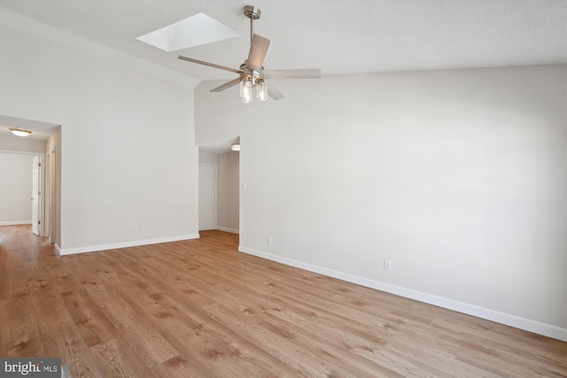 empty room featuring ceiling fan, a skylight, high vaulted ceiling, light hardwood / wood-style floors, and a textured ceiling