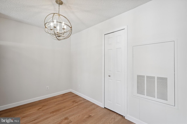 unfurnished room with hardwood / wood-style floors, a textured ceiling, and a notable chandelier