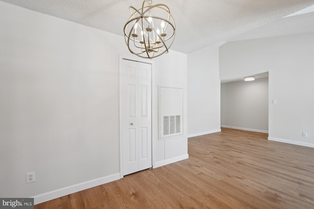 unfurnished dining area featuring a notable chandelier, wood-type flooring, and a textured ceiling