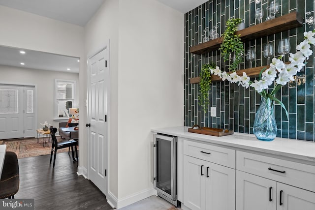 bar with white cabinetry, beverage cooler, dark wood-type flooring, and tasteful backsplash