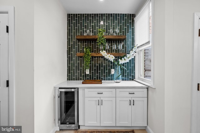 bar featuring white cabinetry, beverage cooler, and tasteful backsplash