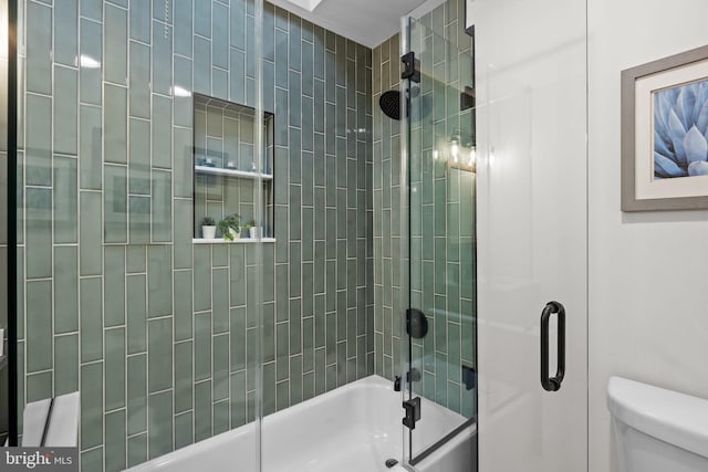 bathroom featuring toilet and combined bath / shower with glass door