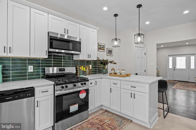 kitchen featuring white cabinetry, stainless steel appliances, and kitchen peninsula