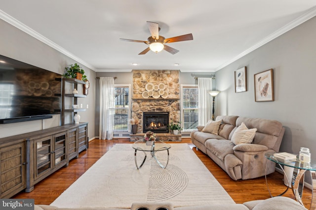 living room with hardwood / wood-style flooring, ceiling fan, ornamental molding, and a fireplace