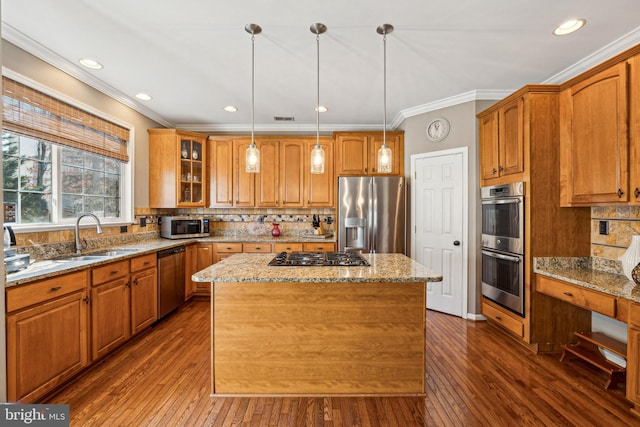 kitchen with appliances with stainless steel finishes, decorative light fixtures, sink, a center island, and light stone counters