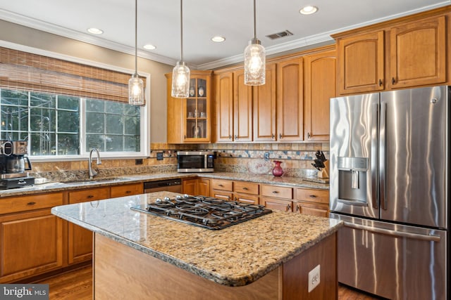 kitchen with hanging light fixtures, a kitchen island, light stone countertops, and appliances with stainless steel finishes