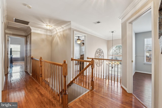 hall with crown molding, hardwood / wood-style floors, and an inviting chandelier