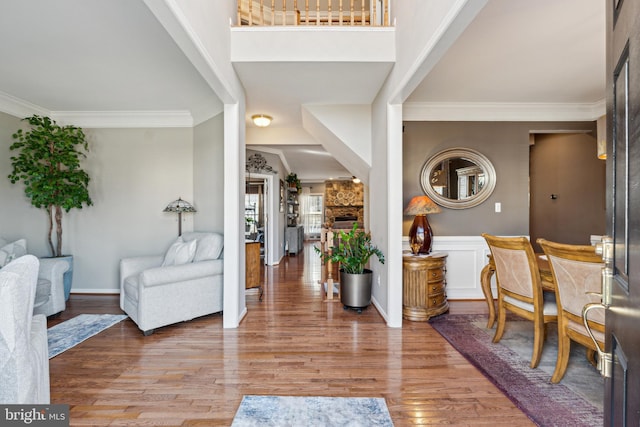 foyer entrance with wood-type flooring, a fireplace, and crown molding