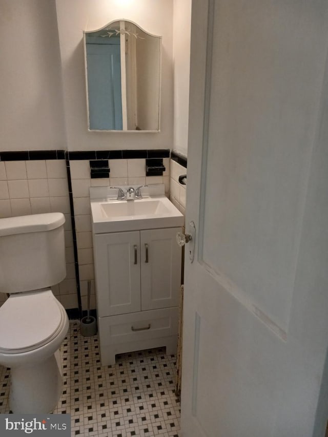 bathroom featuring vanity, tile walls, tile patterned floors, and toilet