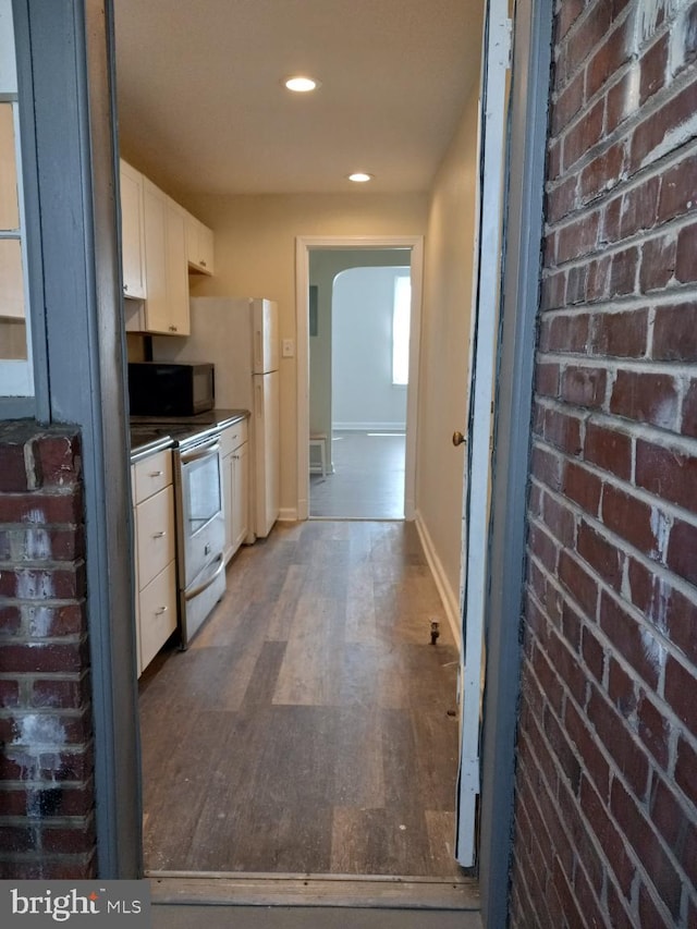 kitchen with white cabinetry, stainless steel electric range oven, and brick wall