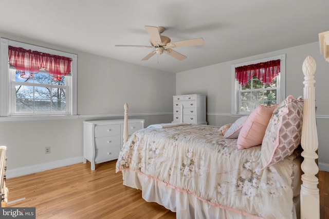 bedroom with ceiling fan, multiple windows, and hardwood / wood-style floors