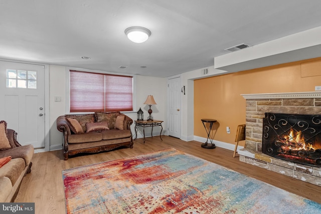 living room with wood-type flooring and a stone fireplace