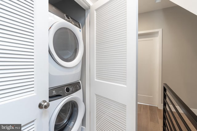 washroom featuring hardwood / wood-style flooring and stacked washer and clothes dryer