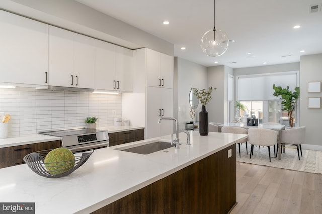 kitchen with stainless steel electric stove, pendant lighting, white cabinets, and dark brown cabinetry