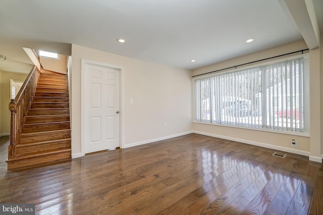 unfurnished room featuring a skylight and dark wood-type flooring