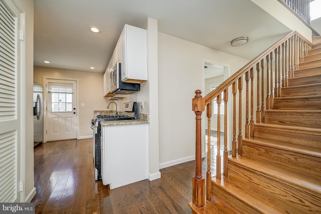 kitchen featuring white cabinetry, light stone counters, dark hardwood / wood-style flooring, and appliances with stainless steel finishes