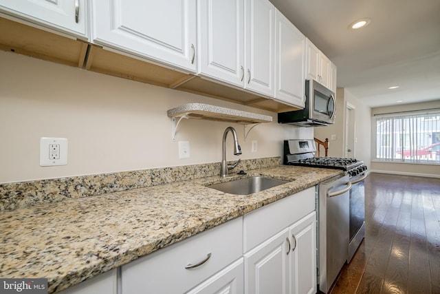 kitchen with sink, light stone counters, appliances with stainless steel finishes, dark hardwood / wood-style floors, and white cabinets