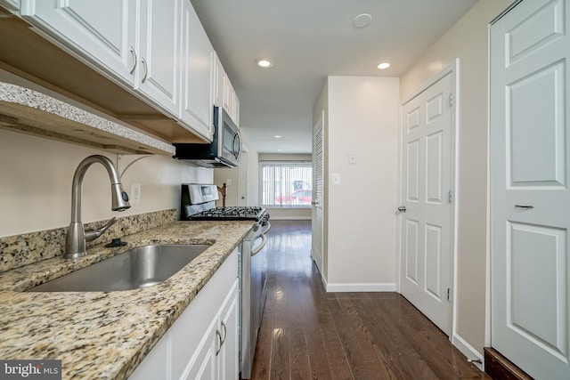 kitchen with dark hardwood / wood-style floors, sink, white cabinets, light stone counters, and stainless steel appliances