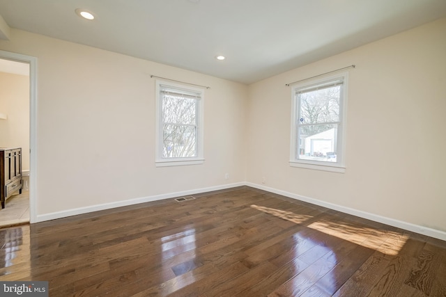 unfurnished room with a wealth of natural light and dark hardwood / wood-style flooring