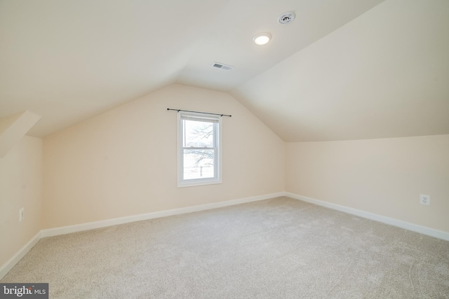 additional living space with light colored carpet and vaulted ceiling