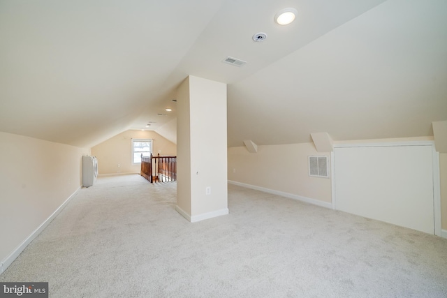 bonus room with light colored carpet and lofted ceiling