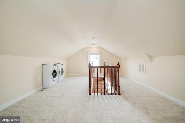 bonus room featuring lofted ceiling, light colored carpet, and washer and clothes dryer