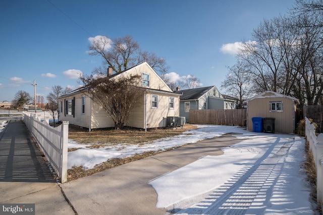 view of snowy exterior featuring a storage shed and central AC