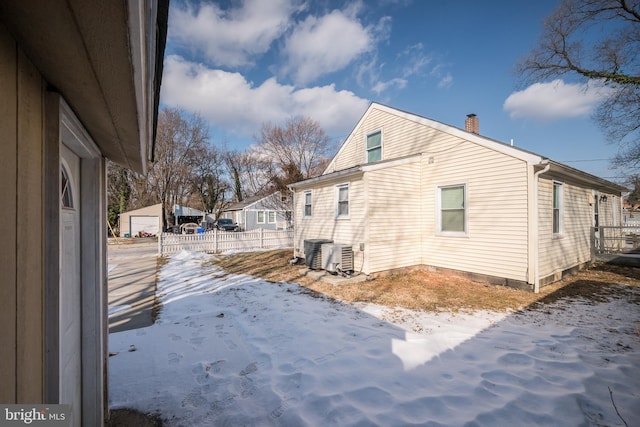 snow covered property with cooling unit and a garage