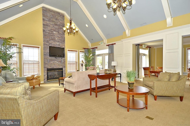 living room featuring high vaulted ceiling, a notable chandelier, a healthy amount of sunlight, a stone fireplace, and light colored carpet