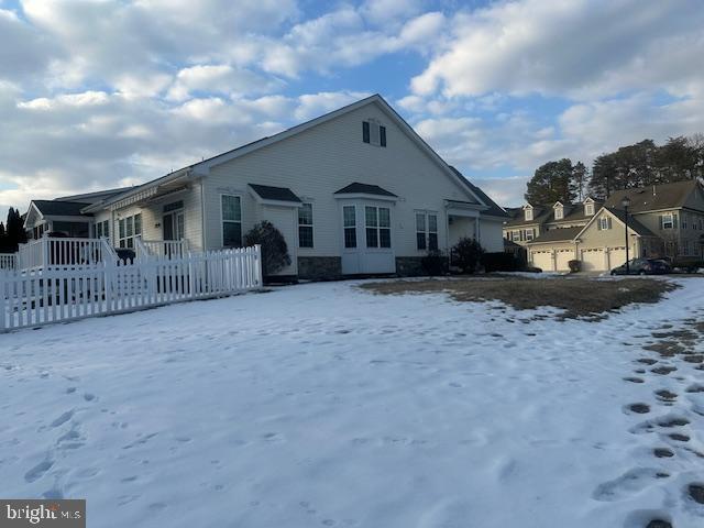 snow covered rear of property featuring a garage