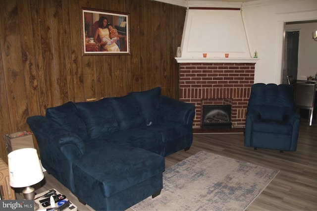 living room featuring crown molding, hardwood / wood-style flooring, a fireplace, and wooden walls