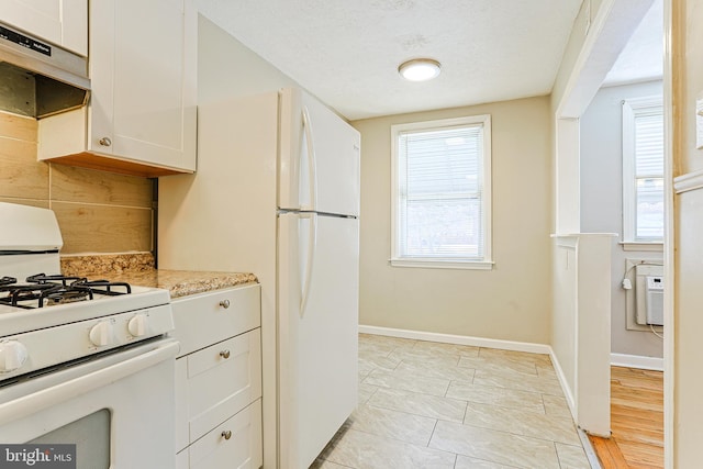 kitchen with white cabinetry, light stone counters, a textured ceiling, and white appliances