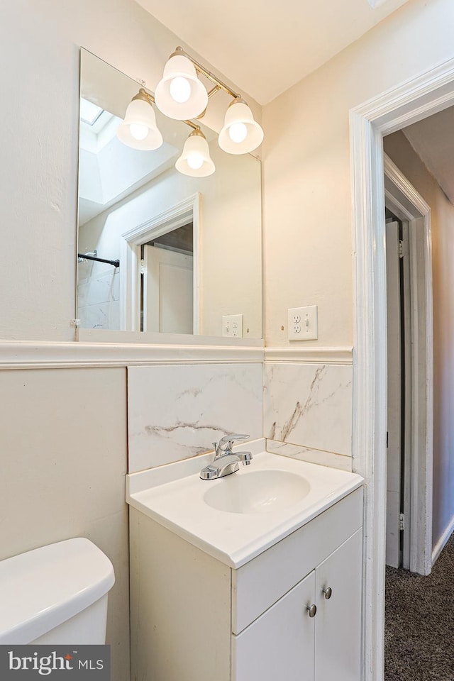 bathroom with vanity, decorative backsplash, toilet, and tile walls