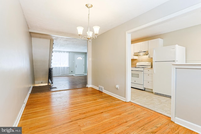 unfurnished dining area with a chandelier and light wood-type flooring