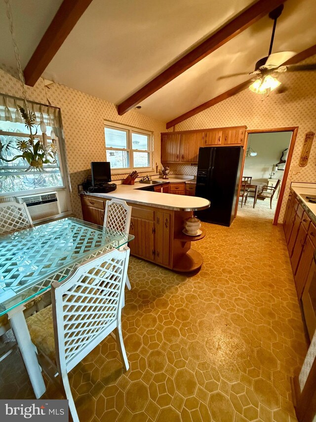 kitchen featuring vaulted ceiling with beams, wallpapered walls, brown cabinets, a peninsula, and black fridge with ice dispenser