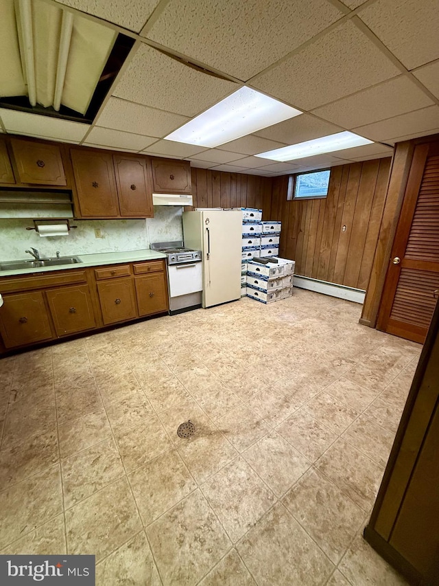 kitchen with a sink, a baseboard heating unit, freestanding refrigerator, brown cabinetry, and gas range